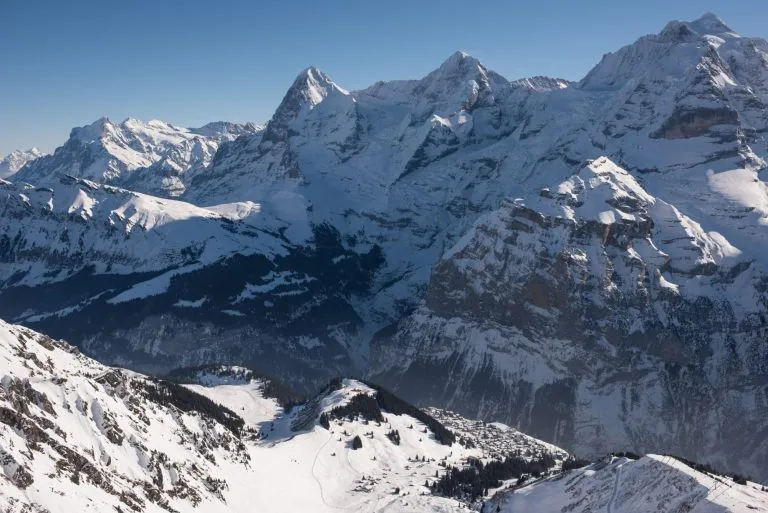 the famous mountains in switzerland eiger monk and jungfrau, below in the picture the mountain village mürren which can be reached only with the aerial cableway ore walking.