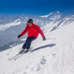 Junger glücklicher Mann beim Skifahren im Skigebiet Lenzerheide, Schweiz.
